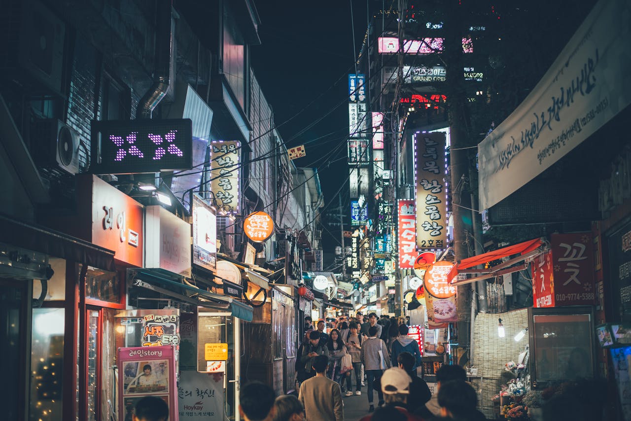 about-01 Bustling night market street in Seogyo-dong, Seoul with neon lights and crowds.